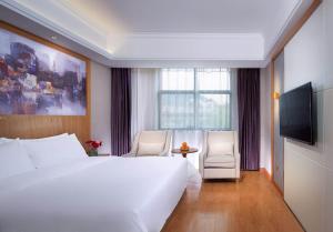 una camera d'albergo con un grande letto bianco e una TV di Vienna 3 Best Hotel (Ganzhou shangyou store) a Yuanzicha