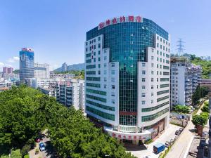 ein hohes Glasgebäude mitten in einer Stadt in der Unterkunft Vienna Hotel Shenzhen Luofang in Shenzhen
