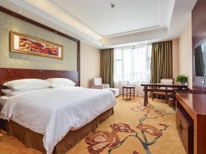 Vienna Hotel Suzhou Yangcheng Lake Huayi Movie World في Zhengyi: غرفة الفندق بسرير كبير ومكتب