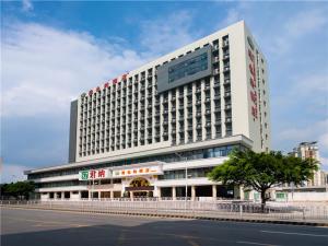 Un grand bâtiment blanc avec un panneau en haut dans l'établissement Vienna Hotel Shenzhen East Railway Station, à Shenzhen