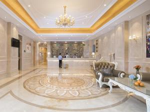 Ein Mann steht in einer großen Lobby mit einem Kronleuchter. in der Unterkunft Vienna Hotel Guangxi Nanjing Nanhu Park in Nanning