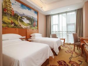 a hotel room with two beds and a painting on the wall at Vienna Hotel Nanjing Olympic Sports Center in Nanjing