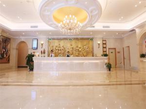 a large lobby with a chandelier and a cash register at Vienna International Hotel Yantai Changjiang Road Xingyi Square Branch in Yantai