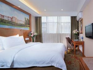 a hotel room with a large bed and a desk at Vienna Classic Hotel (Anlu Hengkun) in Zhulin +6 photos