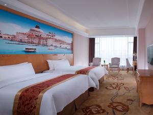 a hotel room with three beds and a television at Vienna Hotel Dongguan Hou Avenue Jinzuo in Hetian