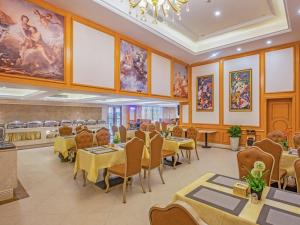 a restaurant with tables and chairs and paintings on the walls at Vienna Hotel (Mulian West Road Shop, Changsha) in Changsha