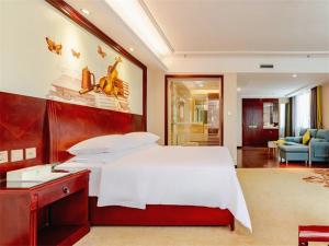 a bedroom with a large white bed and a living room at Vienna Hotel Guilin Railway Staion in Guilin