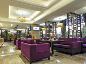 un restaurante con sillas moradas, mesas y ventanas en Vienna Hotel Dongguan Gaobu, en Dongguan