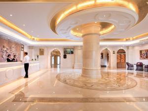 a man standing in a hotel lobby with a column at Vienna International Hotel Huazhou East Beijing Road in Dongshan