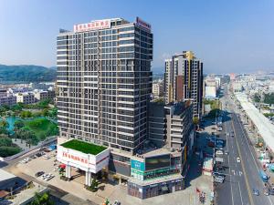 a large tall building in a city with a street at Vienna International Hotel Huizhou Huidong Honghaiwan in Huidong