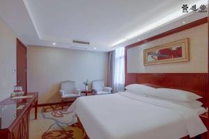 a bedroom with a large white bed and two chairs at Vienna Hotel Changsha Mid Furong Road in Changsha