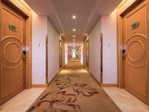 a hallway with a carpet in a building with doors at Vienna International Hotel Huazhou East Beijing Road in Dongshan