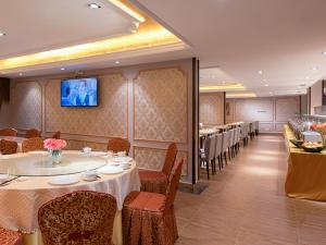 a dining room with tables and chairs and a television at Vienna International Hotel Huizhou Huidong Honghaiwan in Huidong
