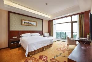 une chambre avec un lit, un bureau et une fenêtre dans l'établissement Vienna Hotel Suzhou Yangcheng Lake Huayi Movie World, à Zhengyi 5 autres photos