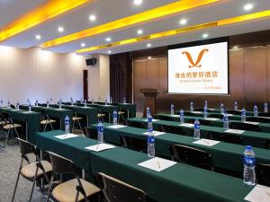 een vergaderzaal met groene tafels en stoelen met flessen water bij Vienna Classic Hotel Guangzhou Yanling Road in Guangzhou
