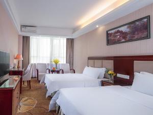 a hotel room with two beds and a television at Vienna Hotel Longgang Nanlian in Longgang +3 photos