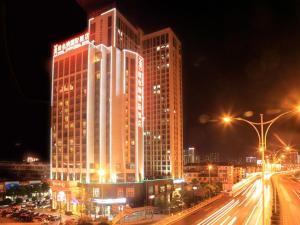 duży wysoki budynek z oświetleniem w nocy w obiekcie Vienna International Hotel Changsha West Bus Station w mieście Changsha