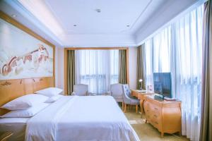 a bedroom with a bed and a desk and a television at Vienna International Hotel Guizhou Weng'an Qilong Binfen Moer City in Yinzhan