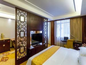 a hotel room with a bed and a flat screen tv at Vienna Hotel Lufeng Peopole Road in Lufeng