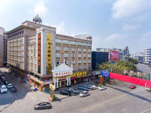 een groot gebouw met auto's geparkeerd op een parkeerplaats bij Vienna Hotel Zhongshan Central Coach Station in Changzhou