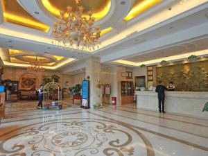 eine Lobby mit einem Kronleuchter und einem Mann, der in einem Hotel steht in der Unterkunft Vienna Hotel Liaocheng University in Liaocheng