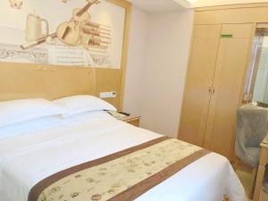 a bedroom with a bed with a guitar on the wall at Vienna Hotel Shenzhen Dongmen Old Street in Shenzhen +2 photos