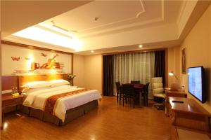 a hotel room with a bed and a desk and a television at Vienna Hotel Ganzhou Anyuan in Tieshan +3 photos