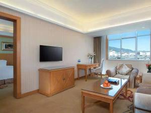 sala de estar con sofá y TV de pantalla plana en Vienna International Hotel Lijiang Yuxue Avenue, en Lijiang