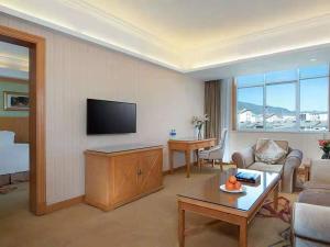 a living room with a couch and a flat screen tv at Vienna International Hotel Lijiang Yuxue Avenue in Lijiang