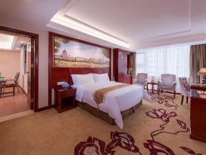 Vienna Hotel Shenzhen Bao'an Xin'an في باوان: غرفه فندقيه بسرير كبير وصاله