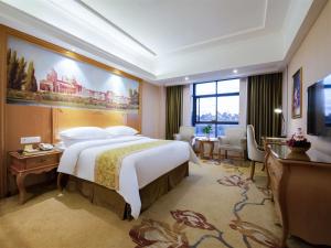 a bedroom with a large bed and a large painting on the wall at Vienna Hotel Qinzhou North Area Plaza in Qinzhou