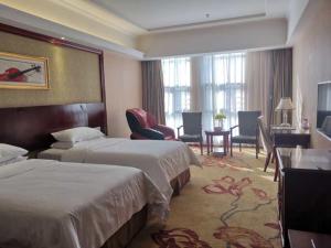 a hotel room with two beds and a desk at Vienna Hotel Chaozhou Plaza in Chaozhou