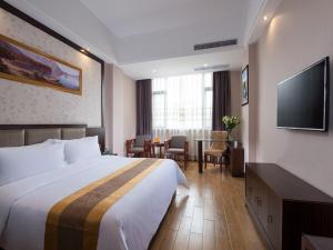 a hotel room with a bed and a flat screen tv at Vienna International Hotel Jieyang Chaoshan Airport in Jieyang