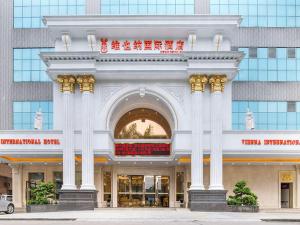 een groot wit gebouw met zuilen voor een gebouw bij Vienna Hotel Dongguan Shi in Dongguan