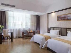 um quarto de hotel com duas camas e uma mesa e cadeiras em Vienna International Hotel Jieyang Chaoshan Airport em Jieyang