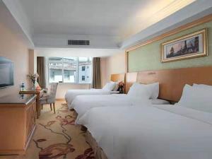 a hotel room with two beds and a television at Vienna International Hotel Lijiang Yuxue Avenue in Lijiang +14 photos