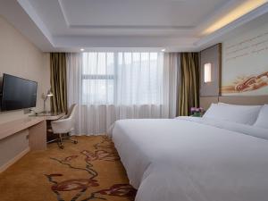 a hotel room with a bed and a desk and a television at Vienna Hotel(Ganzhou Railway Station Shop) in Ganzhou