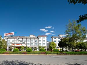 un grande edificio bianco di fronte a una strada di Vienna International Hotel Lijiang Yuxue Avenue a Lijiang
