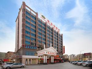 un grand bâtiment avec des voitures garées dans un parking dans l'établissement Vienna Hotel Shaoguan Wujiang Kuangshan Park, à Shaoguan