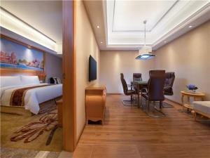 東莞市にあるVienna Hotel Guangdong Gaozhou City East Passenger Depotのベッドとテーブルと椅子のあるホテルの部屋
