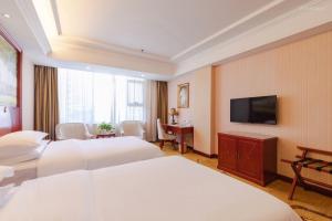 a hotel room with two beds and a flat screen tv at Vienna Hotel Shenzhen Bao'an Xin'an in Bao'an