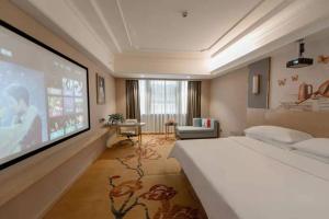 a bedroom with a bed and a flat screen tv at Vienna International Hotel (Hunan Changde Taoyuan Longba) in Taoyuan