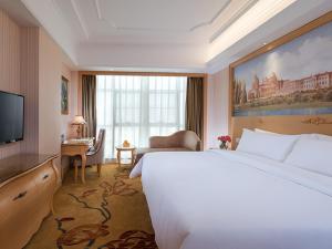 una camera d'albergo con un grande letto e una TV di Vienna International Hotel Shenzhen Longhua Center a Bao'an