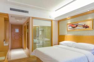 a bedroom with a large white bed and a bathroom at Vienna Hotel Hubei Tianmen Donghu International in Tianmen
