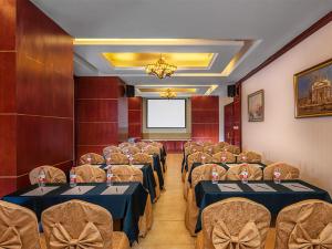 a conference room with tables and chairs and a screen at Vienna International Hotel Changsha Furong Plaza in Changsha