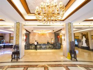 a man standing in a lobby with a chandelier at Vienna Hotel Lufeng Peopole Road in Lufeng