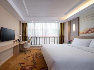 カン州市にあるVienna Hotel(Ganzhou Railway Station Shop)のベッド、デスク、テレビが備わるホテルルームです。