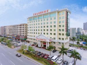 un gran edificio con coches estacionados en un estacionamiento en Vienna International Hotel Shenzhen Longhua Center en Bao'an
