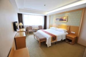 a hotel room with a bed and a television at Vienna Hotel Qidong South Gongyuan Road in Qidong