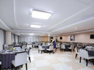 a woman standing in a dining room with tables and chairs at Vienna International Hotel Nanchang Xinjian Center in Nanchang